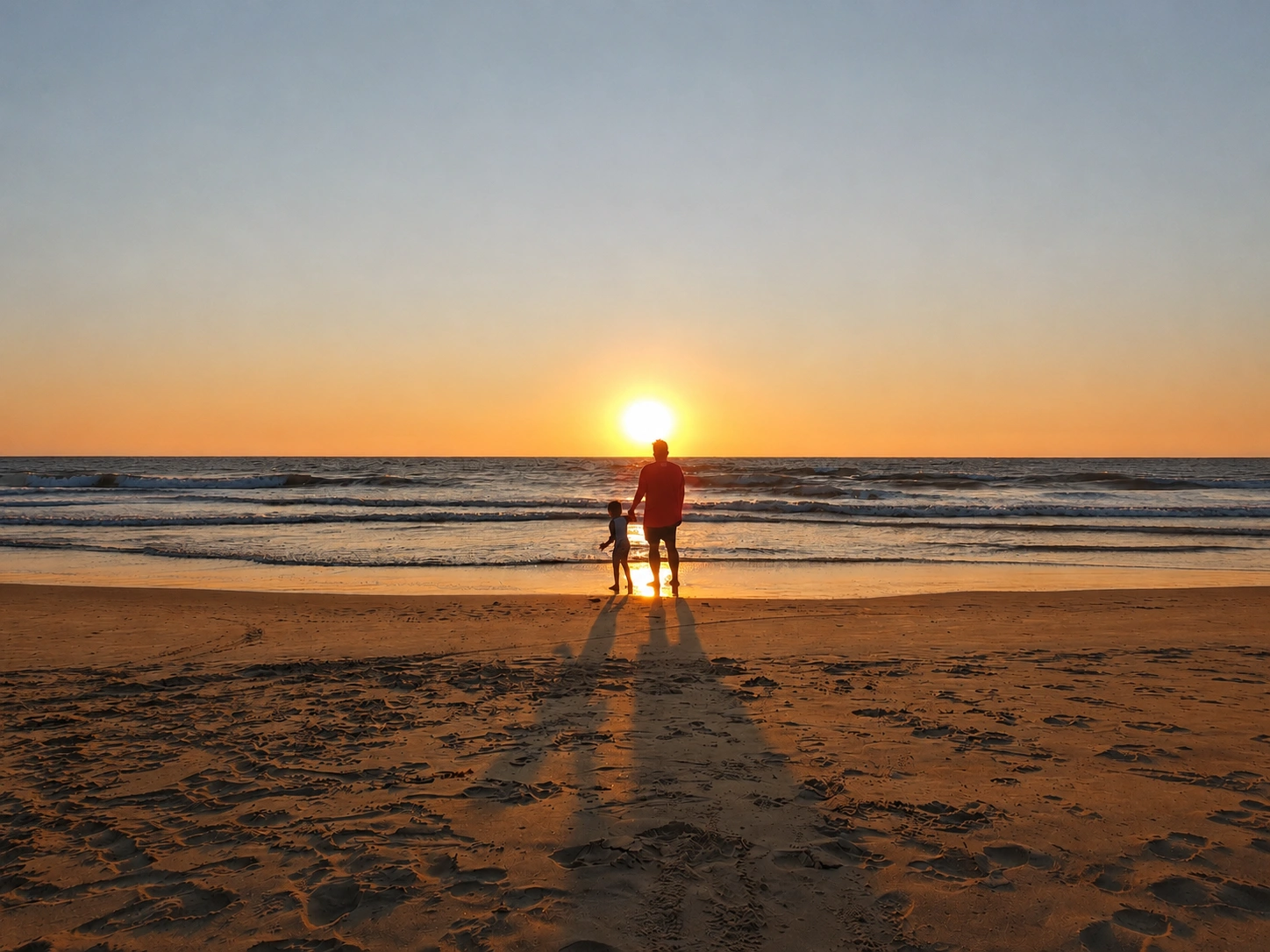 Parent and child by the sea at sunset